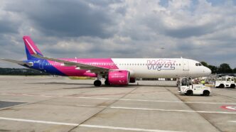 Airbus A321neo linii Wizz Air w różowo-fioletowych barwach zaparkowany na płycie postojowej lotniska Kraków-Balice.