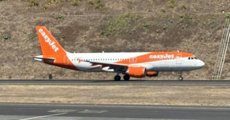 Samolot Airbus A320 w pomarańczowo-białych barwach easyJet kołuje po pasie startowym na tle zbocza porośniętego suchą trawą