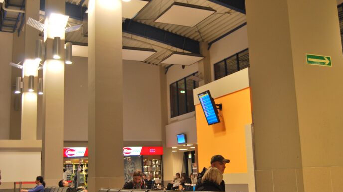 Poczekalnia terminalu lotniska z siedzącymi pasażerami