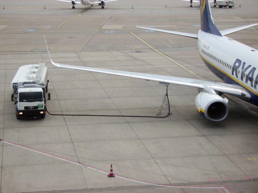Cysterna paliwowa podłączona do skrzydła Boeinga 737 Ryanaira stojącego na płycie lotniska